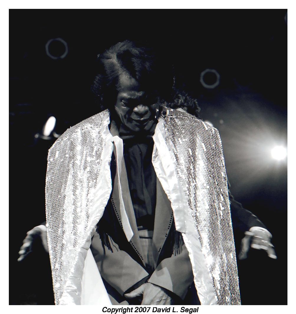 James Brown being a showman wearing a cape during his musical act